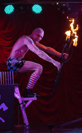 Finhead starts to sit on extreme bed of nails with burning candelabra during live performance